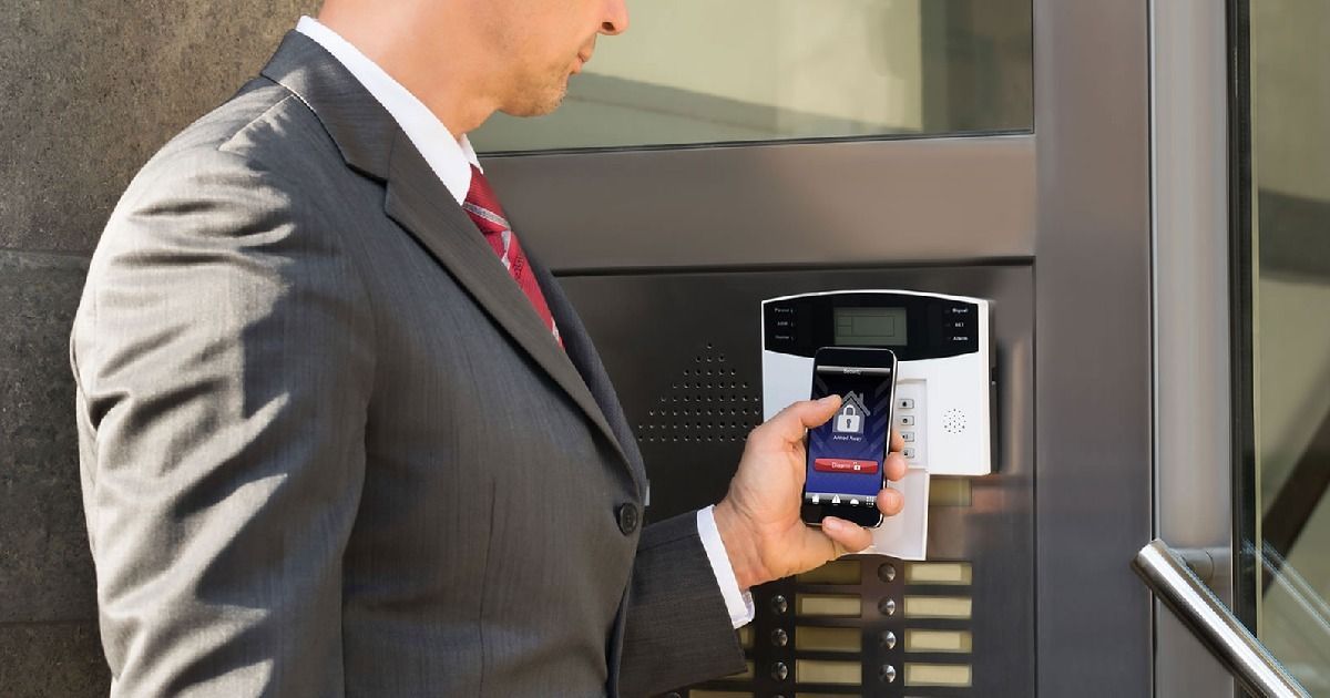 Man in a suit unlocking a door with his smartphone, showing a lock icon on screen.