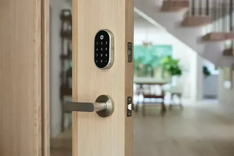 Smart lock on a wooden door with a keypad and lever handle; interior of a home.
