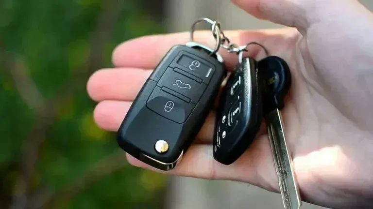 Hand holding car keys with remote and ignition key.