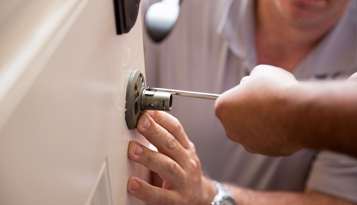 Person using a screwdriver to repair a door lock.