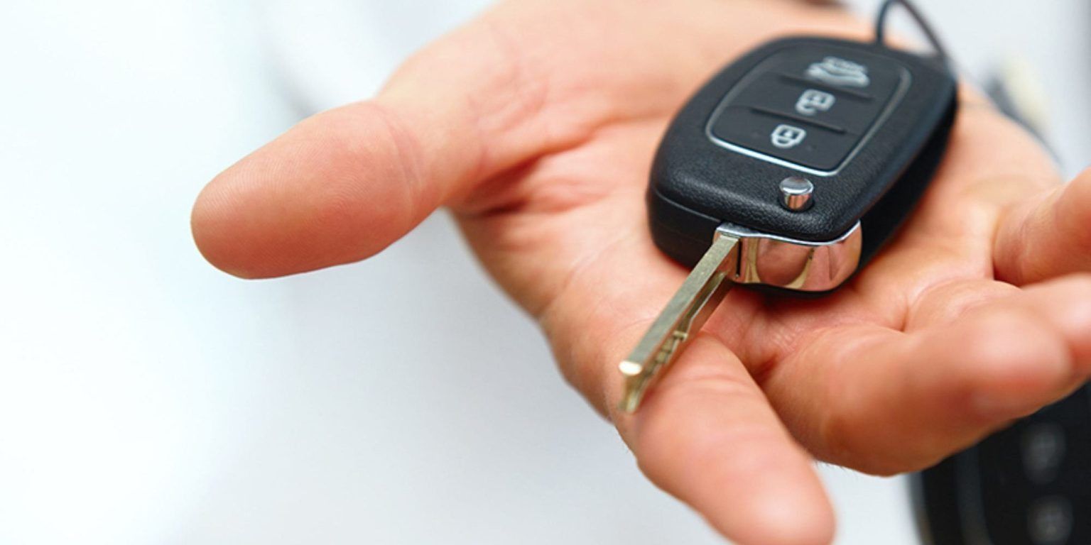 Hand holding a black car key with silver key head.