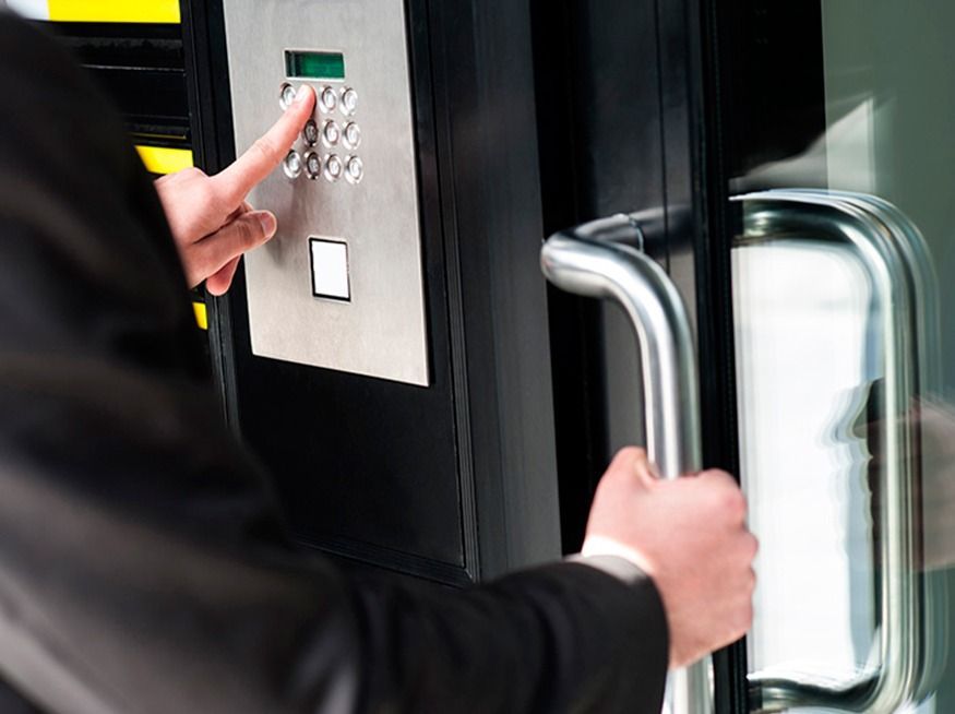 Person in suit entering a building, using a keypad to unlock the door.