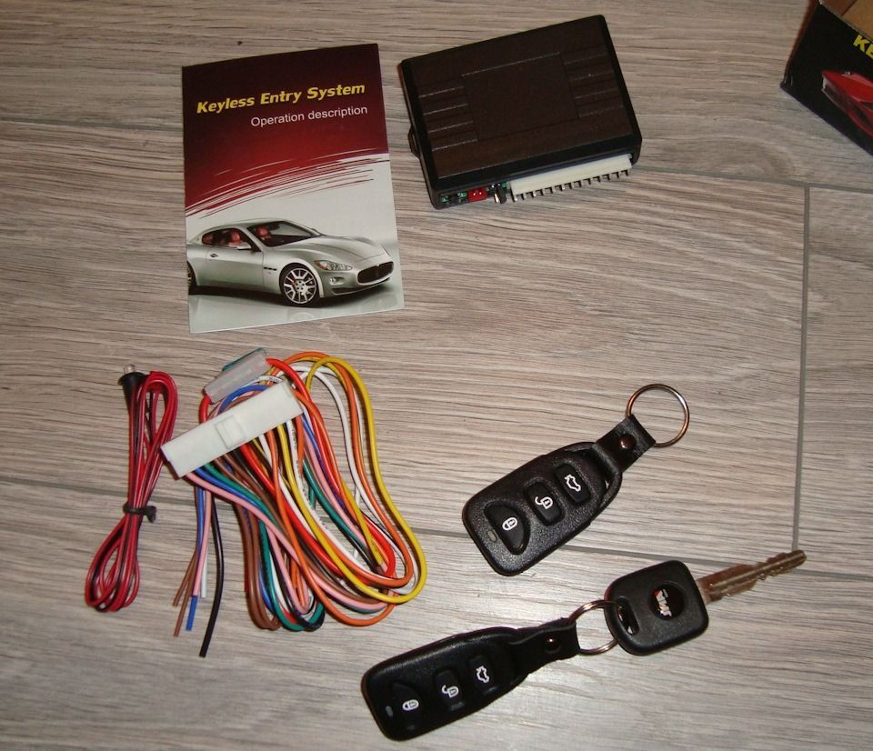 Car keyless entry system kit with remote fobs, control module, wiring harness, and manual.