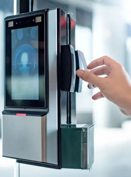 A person uses a card to access a security device with facial recognition on a glass door.