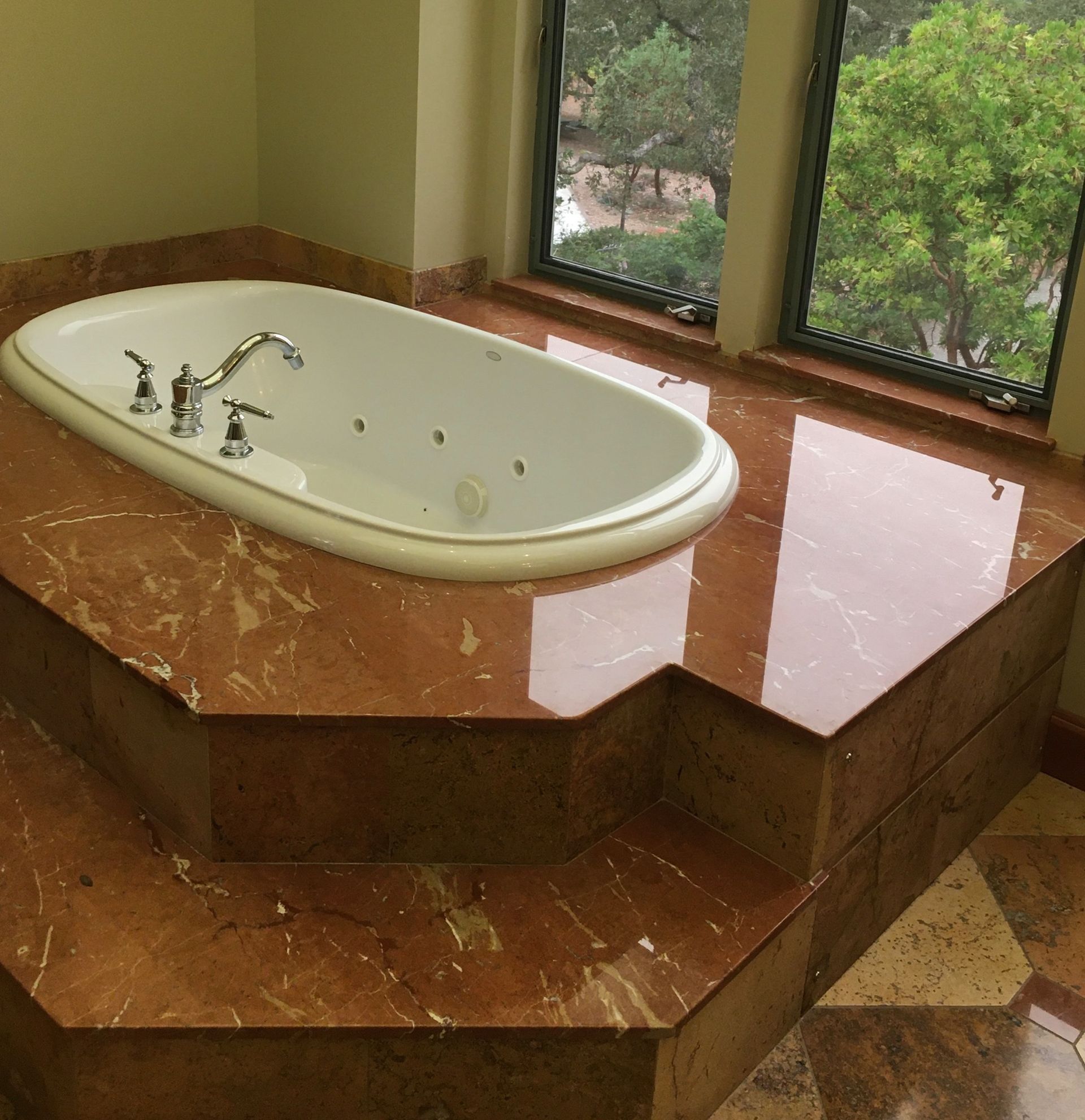 A bathtub sitting on top of a marble counter next to a window