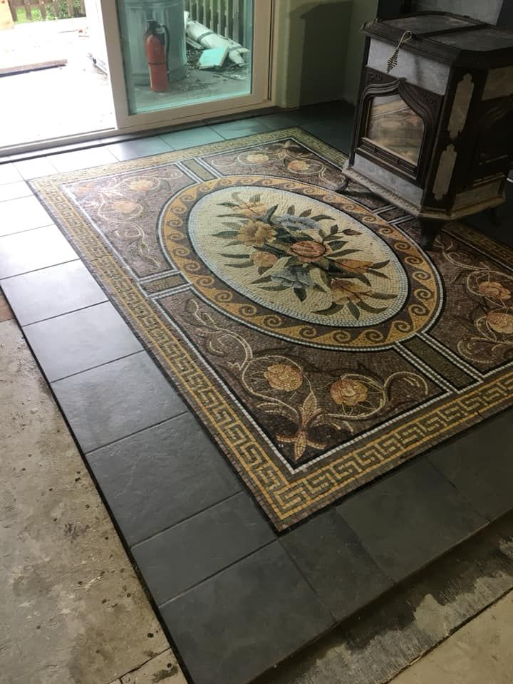 A rug is sitting on top of a tiled floor next to a fireplace.