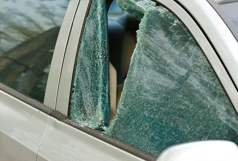 Un coche con una ventana rota está estacionado al costado de la carretera.
