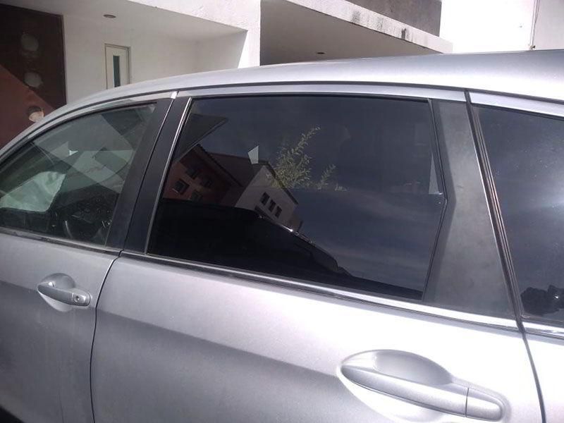 Un coche plateado está aparcado delante de una casa.