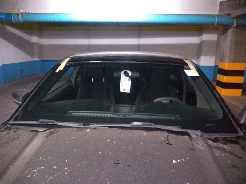 Un coche con una placa en el parabrisas está aparcado en un garaje.