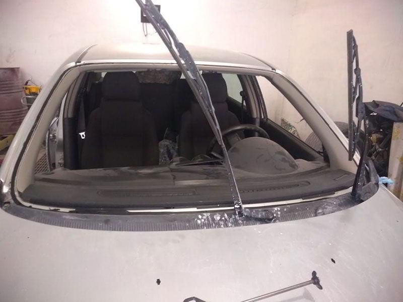 Un coche plateado con el limpiaparabrisas levantado.