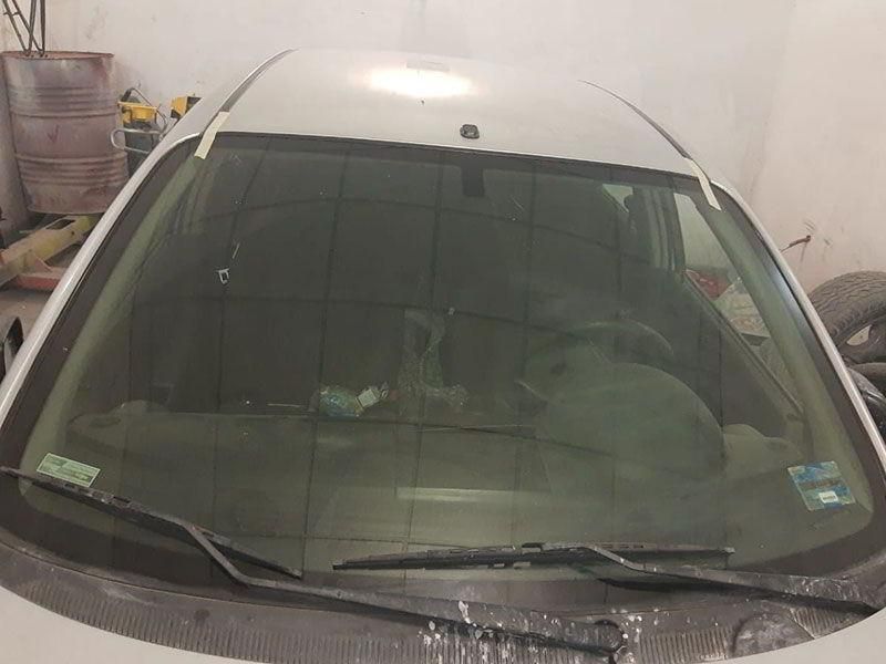 Un coche blanco con el parabrisas roto está aparcado en un garaje.