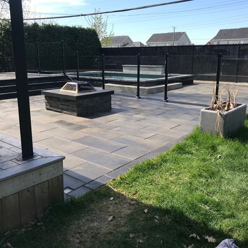 Un patio avec un foyer et une piscine en arrière-plan.