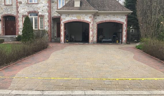 Une allée en briques menant à une grande maison avec deux garages.