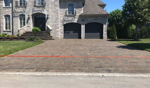 Une grande allée en briques menant à une grande maison avec deux garages.