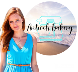 A woman in a blue dress stands in front of a logo for antioch bakery