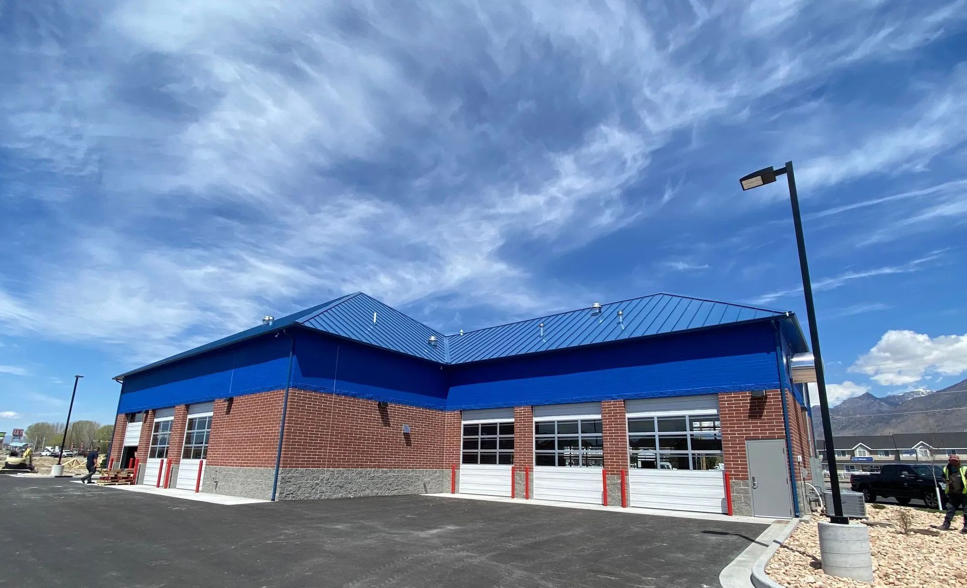 Car wash building with blue roof and brick facade under a cloudy sky.