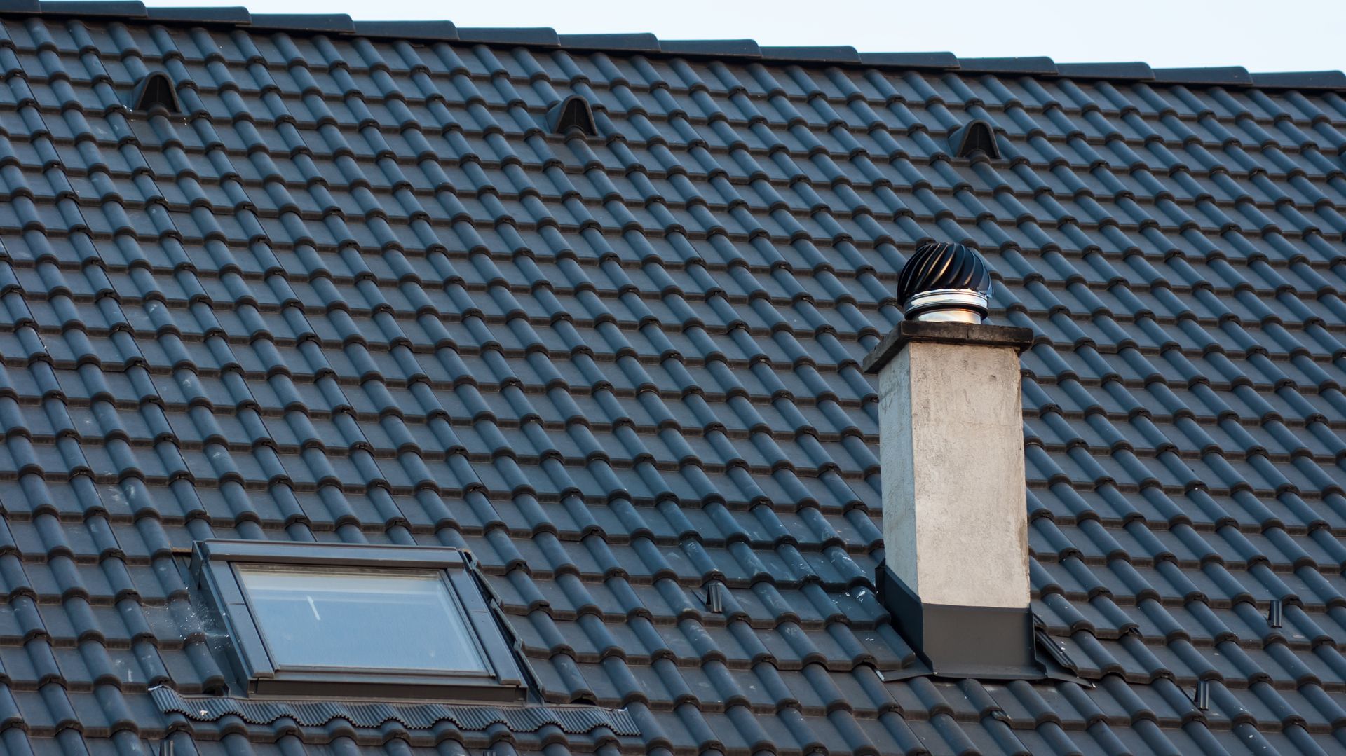 A roof with a chimney and a skylight on it.