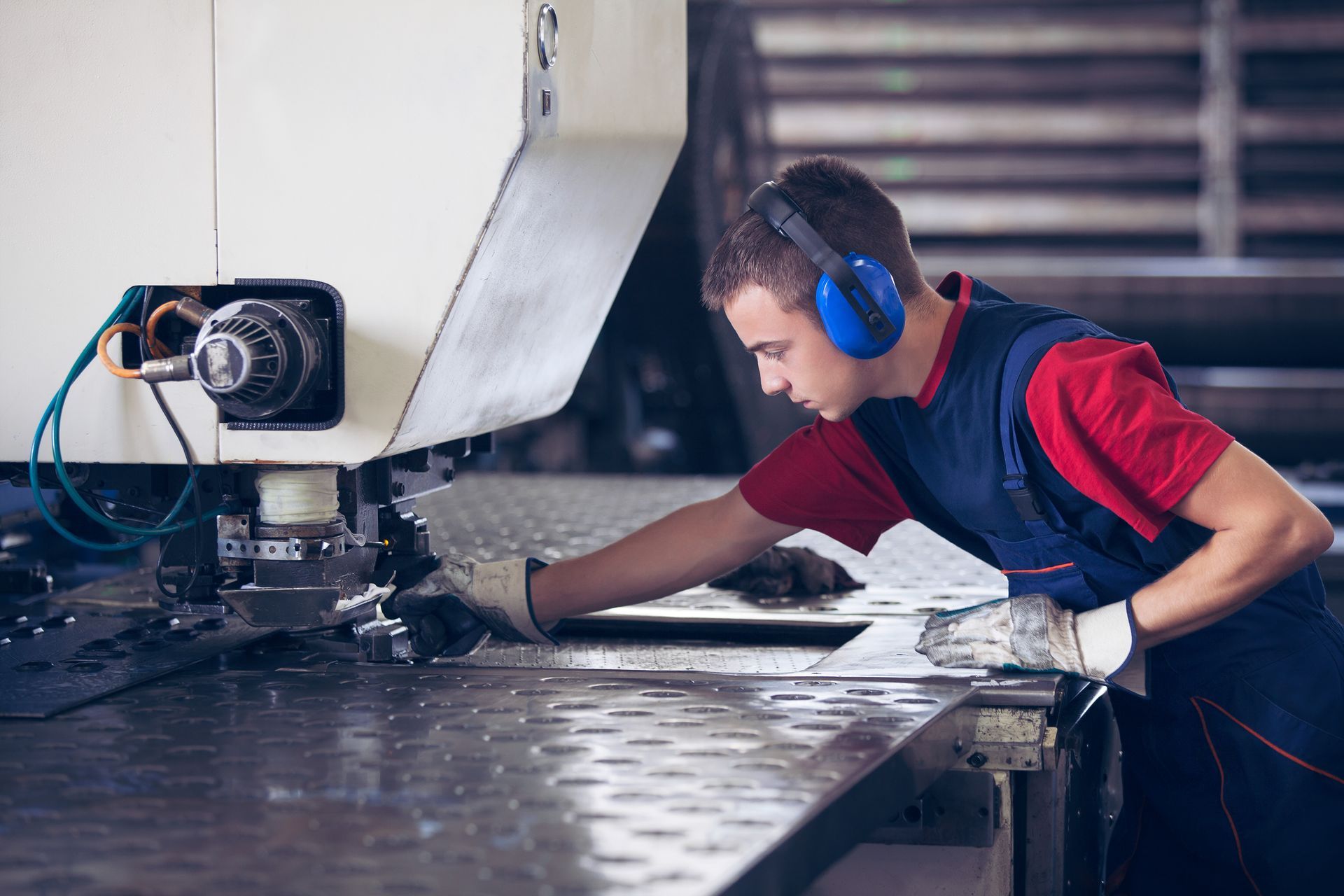 A man wearing headphones is working on a machine in a factory.