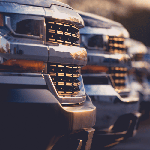 Close-up of silver semi-truck grilles lined up in a row at sunset