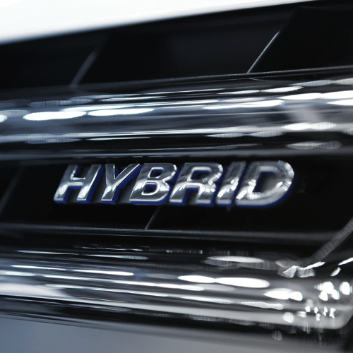 Close-up of a chrome HYBRID badge on a glossy black car trim