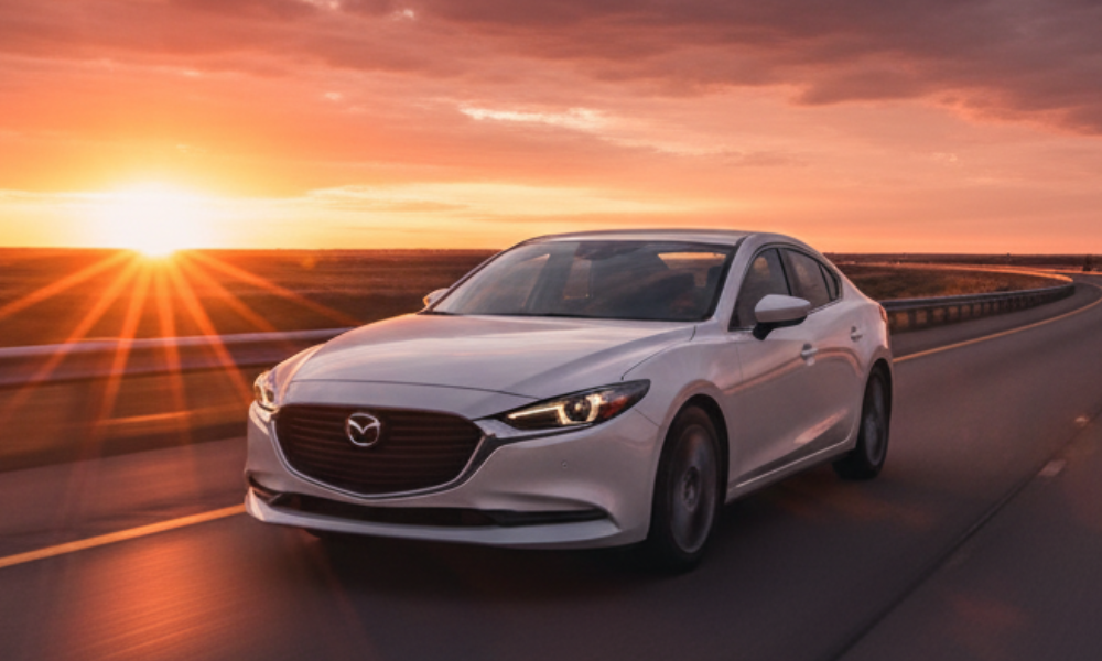 Mazda sedan driving on highway at sunset