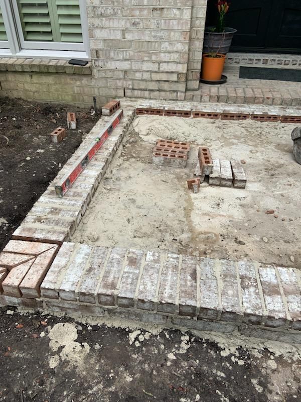 A brick walkway is being built in front of a house.