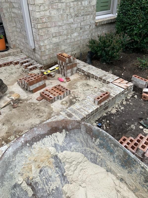 A brick wall is being built on the side of a house.