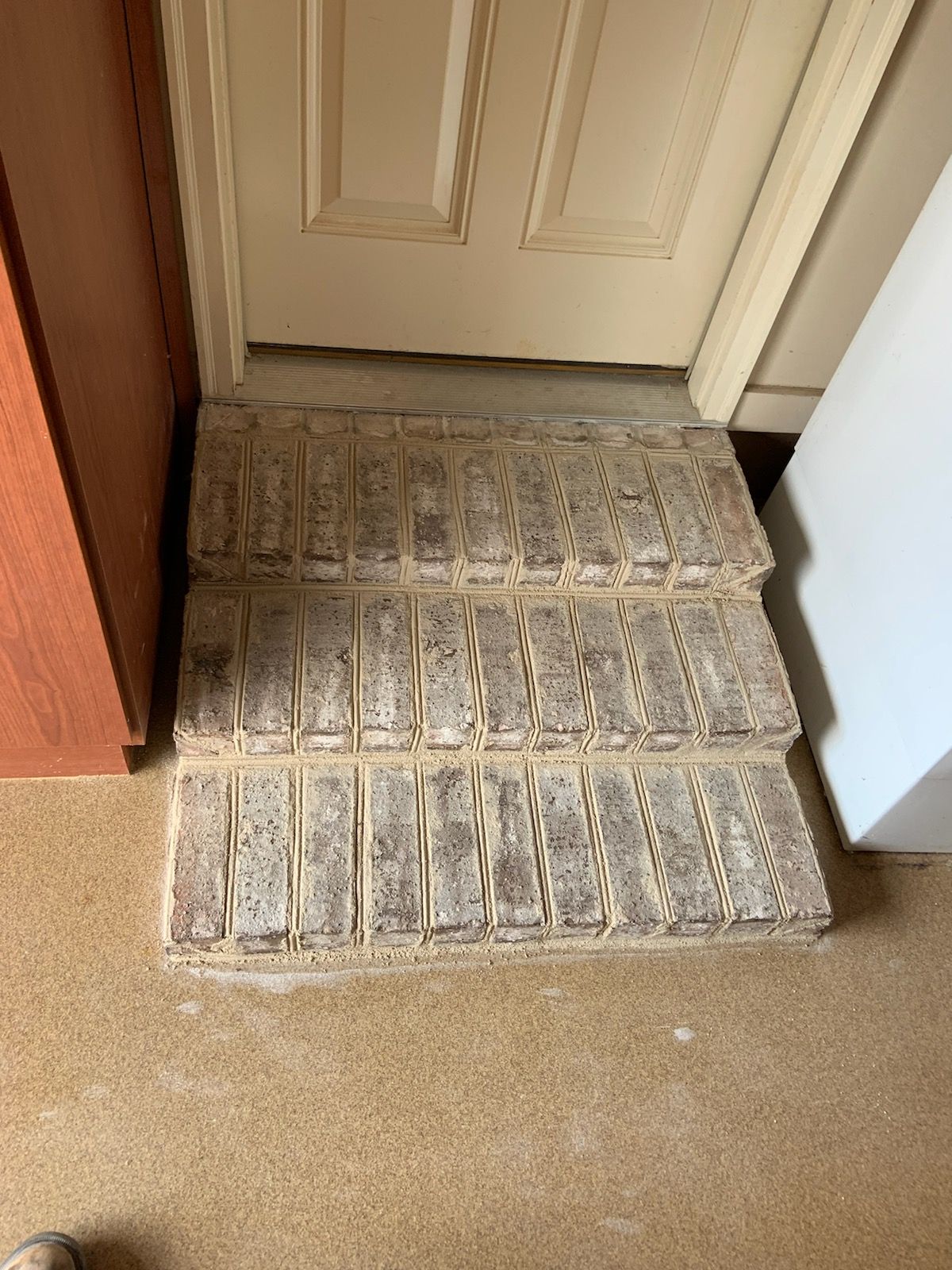 A brick walkway leading to a door in a room.