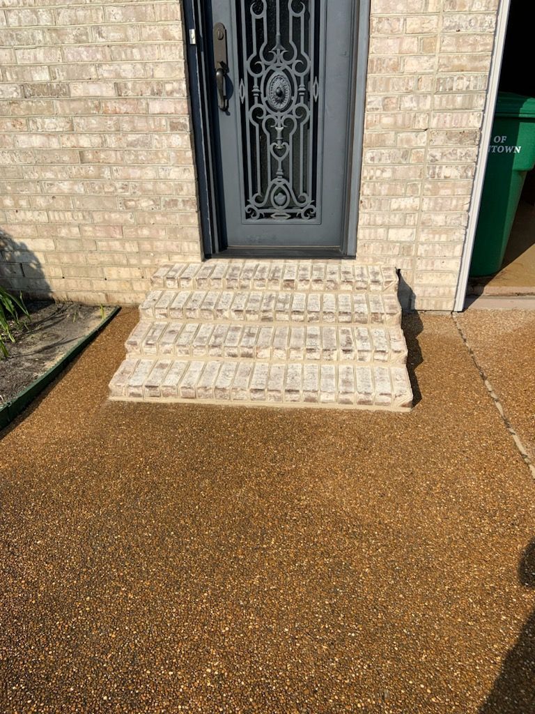 A brick house with a black door and steps in front of it.