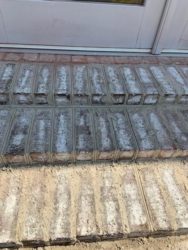 A close up of a brick walkway next to a door.