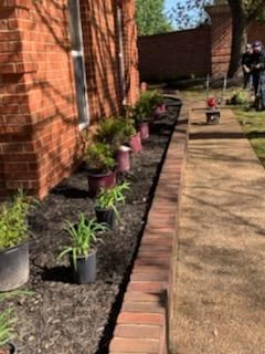 Brick building with planters alongside a brick walkway and lawn.