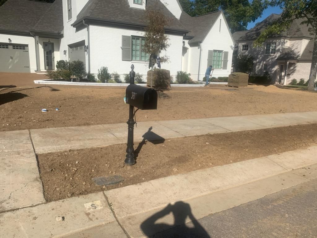 Black mailbox in front of a white house; brown yard; sidewalk and street present.