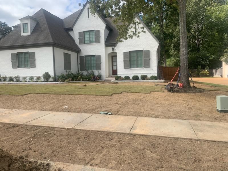 White house with gray shutters, fresh sod, and sidewalk.