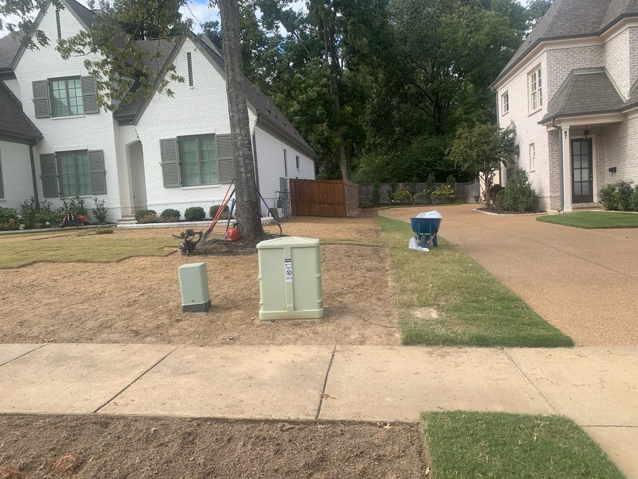 Residential street with homes, landscaping, utility boxes, and freshly laid mulch.