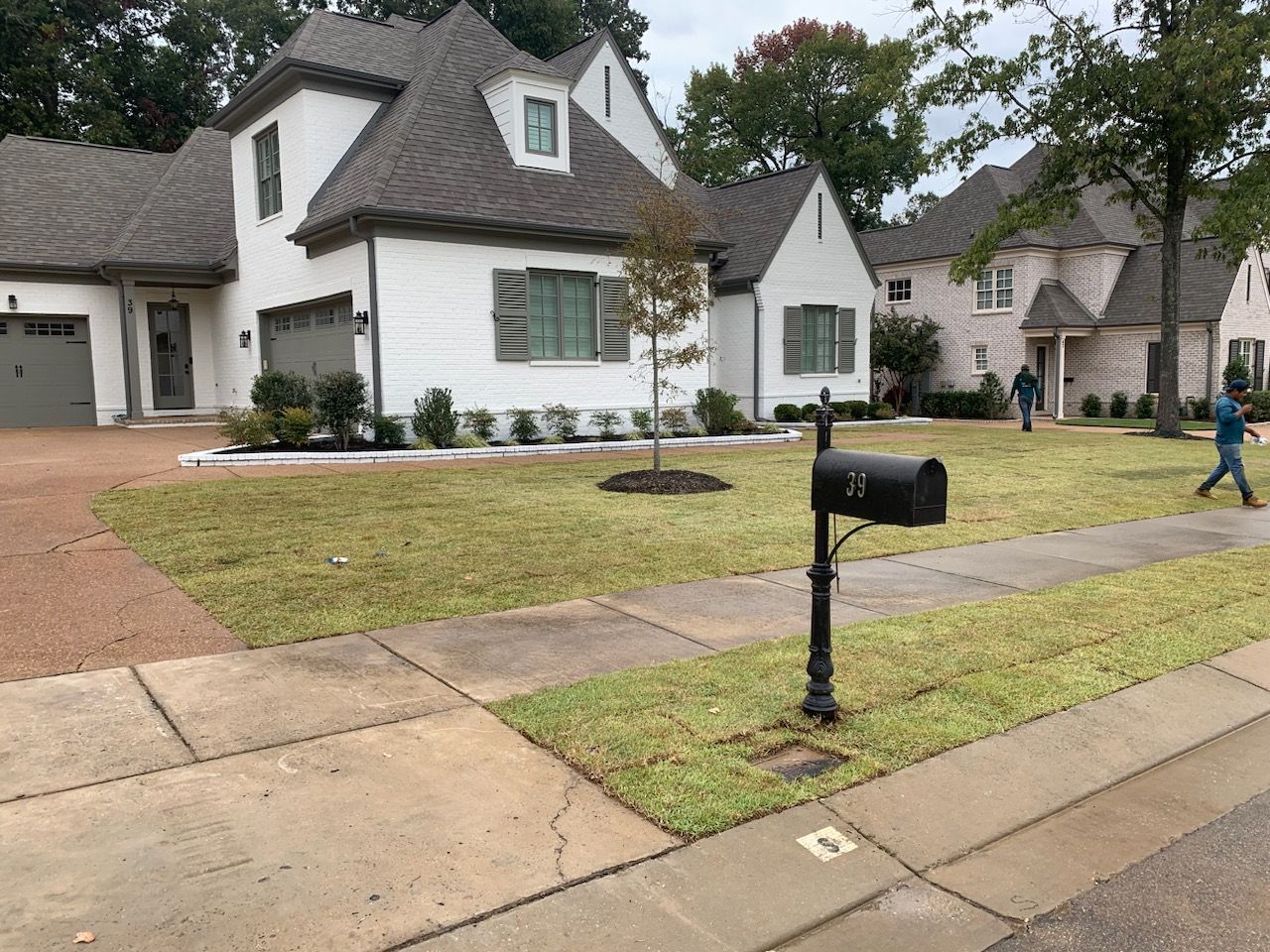 White house with black mailbox in front. Lawn and sidewalk in a suburban setting.