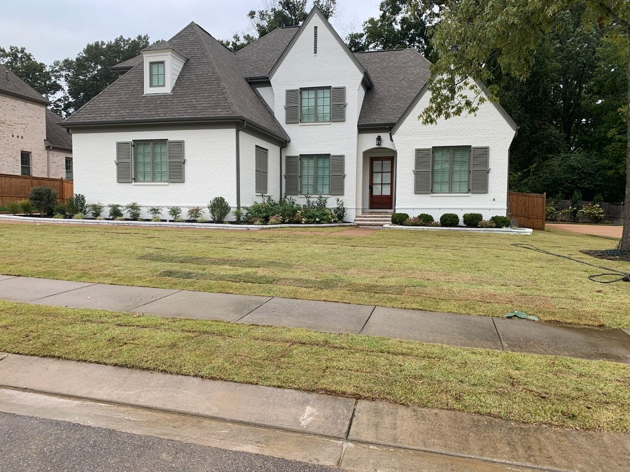 White house with gray roof, green shutters, and front yard.