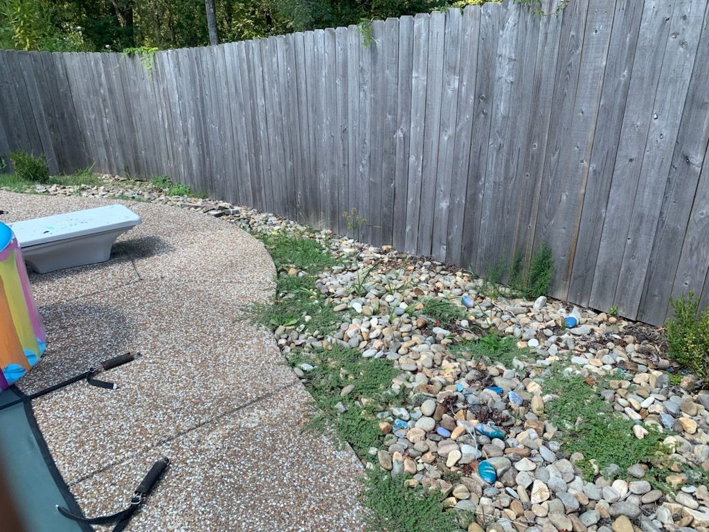 Backyard with gravel patio, stone border, wooden fence, and bench.