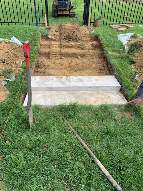 A person is digging a hole in the grass with a shovel.