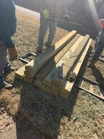 Men arranging stacks of wooden planks on a pallet outdoors.
