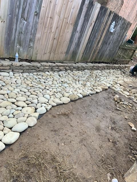 A pebble pathway borders a wooden fence.