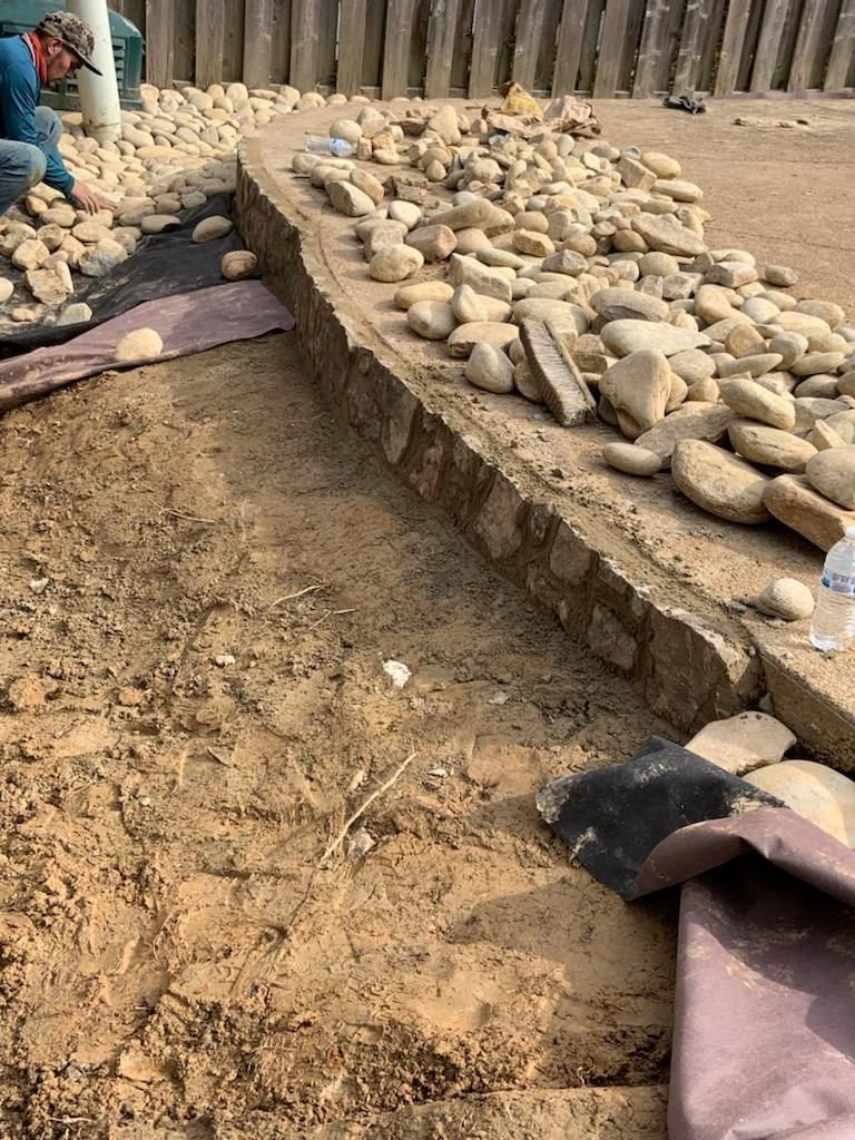 Construction site with rocks, soil, and a person in a blue shirt working.