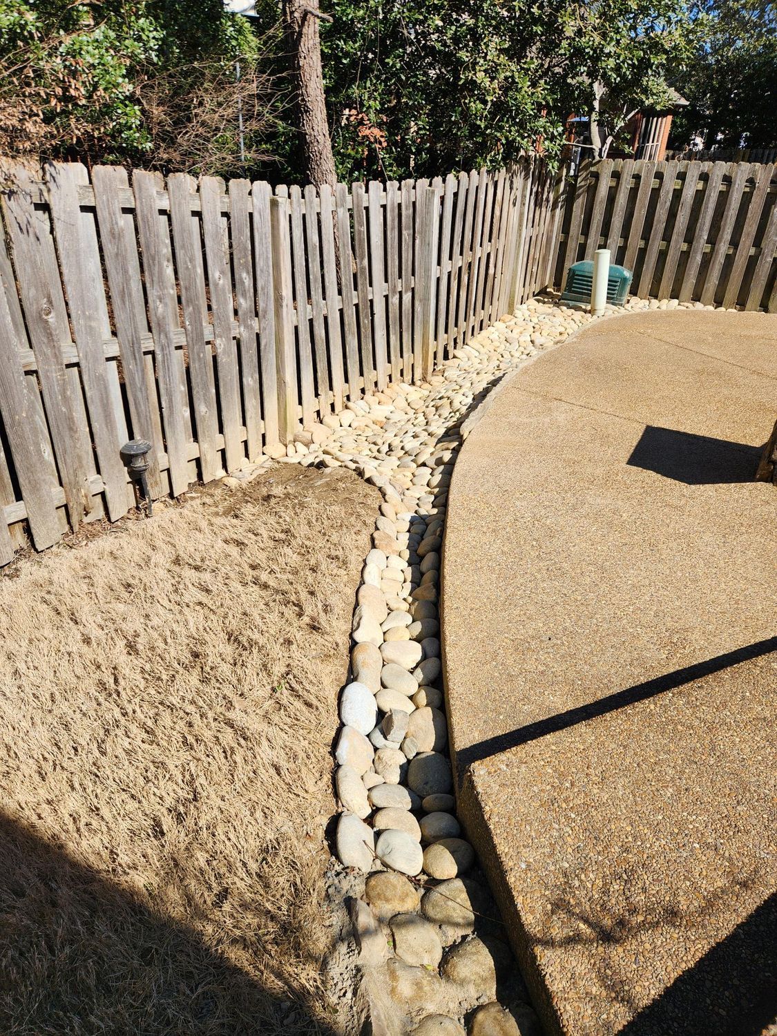 A fenced backyard with a gravel border and a concrete patio.