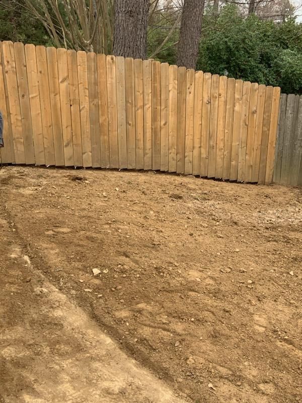 Wooden fence in backyard with dirt and gravel ground.