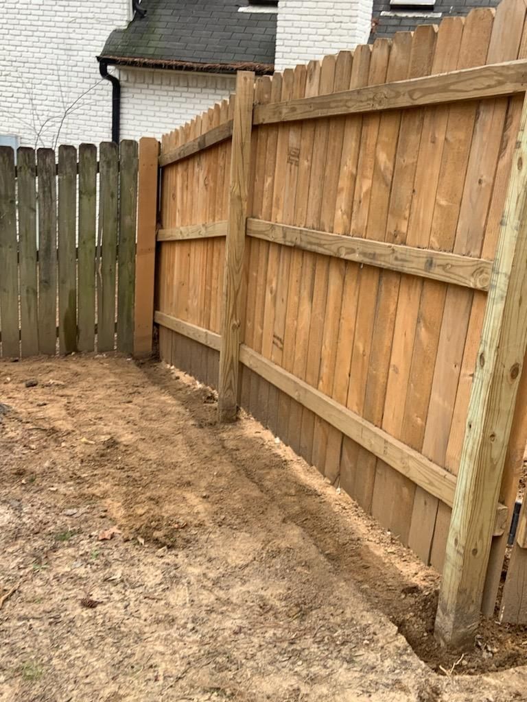 Wooden privacy fence with a dirt path in front.