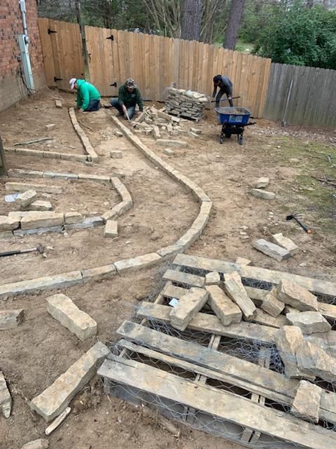 A group of men are working on a patio in a backyard.
