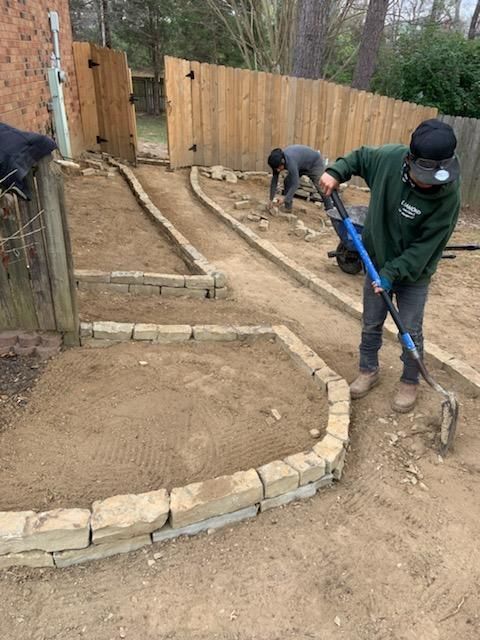 A group of people are working on a path in a backyard.