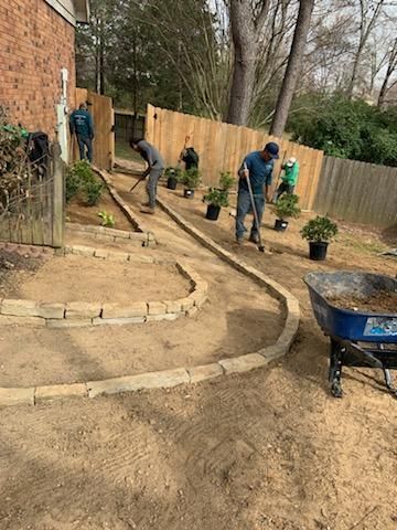 A group of men are working on a patio in a backyard.