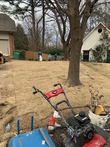 A lawn mower is sitting in the grass in front of a house.