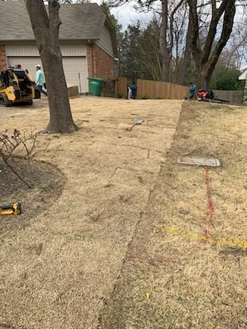 A lawn mower is sitting in the grass in front of a house.