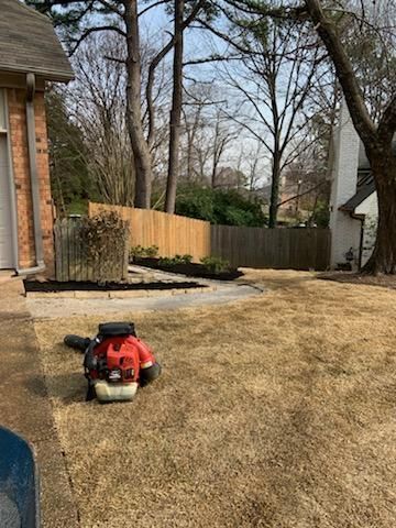 A lawn mower is sitting in the grass in front of a house.
